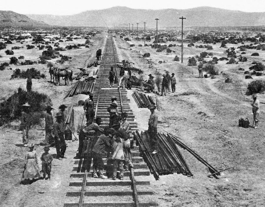 A vintage photo of a group of people on a dirt road.